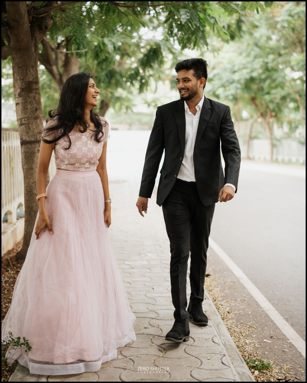 Couple walking and laughing together along a tree-lined street