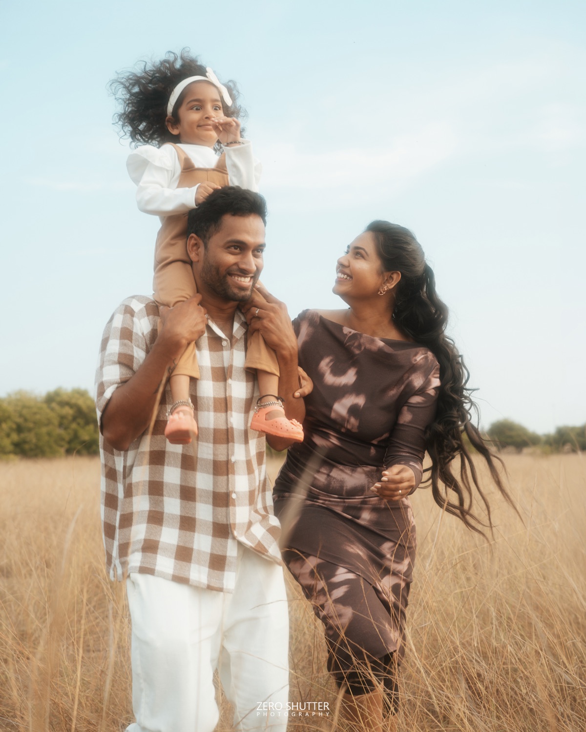Parents and their toddler laughing together in a field