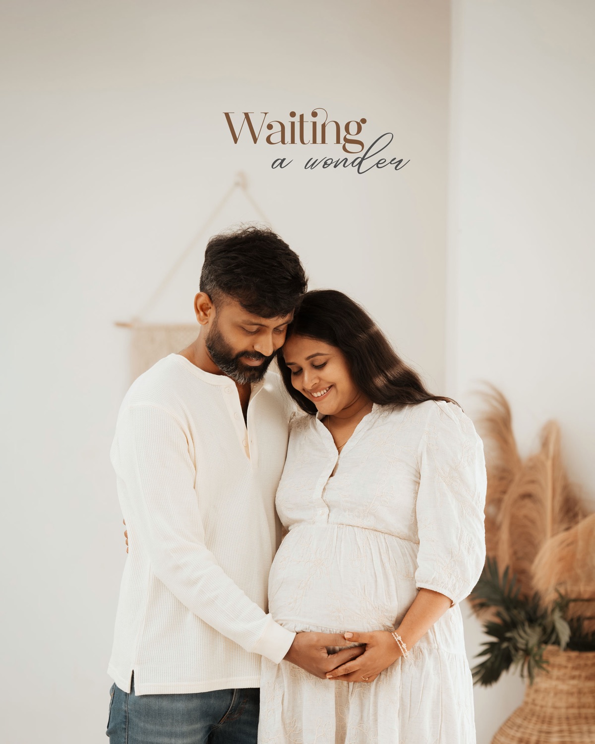 Husband and wife embracing over her bump in a boho studio