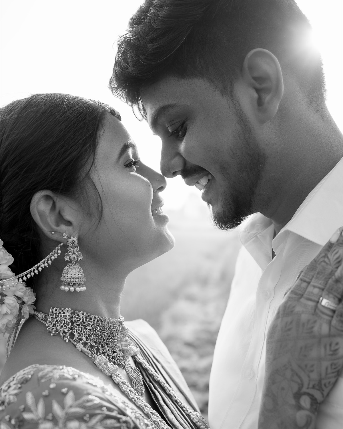 Black and white portrait of a bride and groom nose to nose in the sun