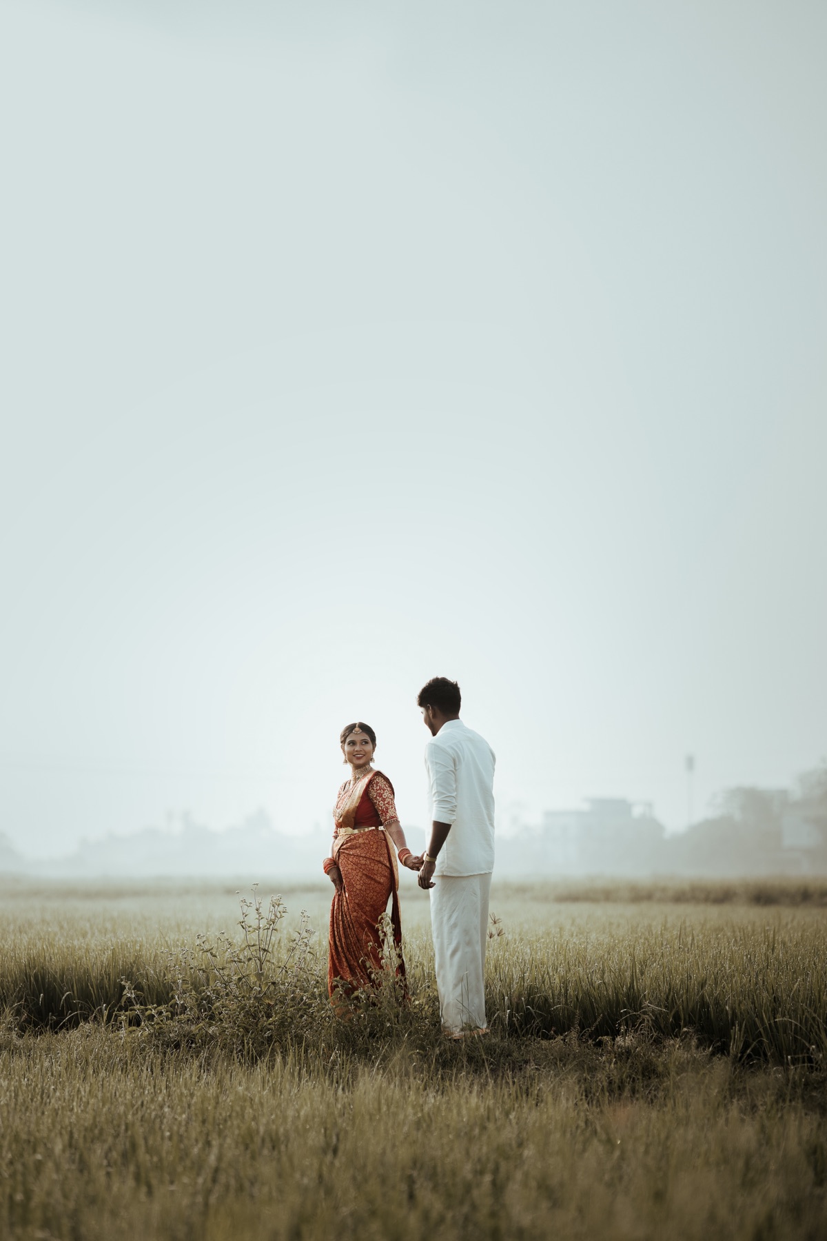 Bride and groom holding hands in a misty paddy field